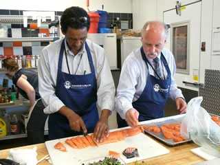 Apprentices Chefs Kifle Hagos and Barry Costa-Pierce preparing salmon slices.